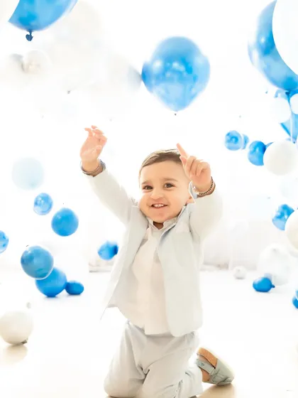 With arms raised in excitement, a one-year-old boy plays amidst a sea of balloons. This candid shot is full of energy and joy, showcasing the fun and interactive nature of my milestone sessions.