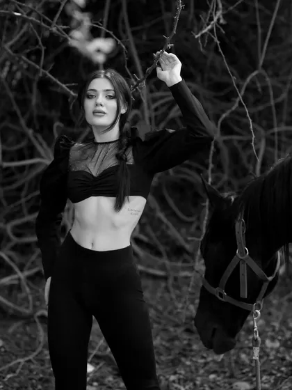 This black and white photo captures a dynamic pose against a dark, wooded background, creating a high-contrast, impactful image.