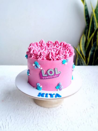 A vibrant pink buttercream cake with a piped floral top. This design uses an edible logo and simple sprinkles for a fun, modern look.