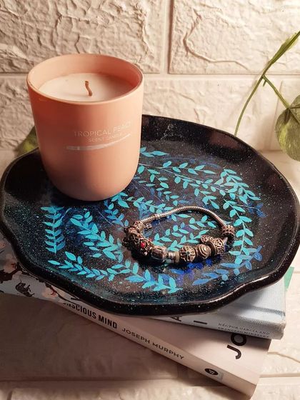 A special hand-painted piece. This is a concrete plate tray that we painted with a delicate leaf pattern over a black, glittery base.
