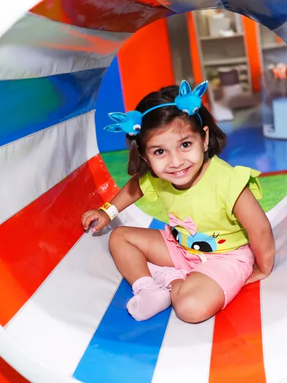 A happy toddler peeks out from our colorful crawl tunnel. These tunnels are perfect for little explorers to navigate safely.