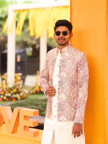 A client looking sharp in a custom jacket with intricate pink and white patterns, worn over a simple white kurta set. A perfect blend of tradition and standout style.