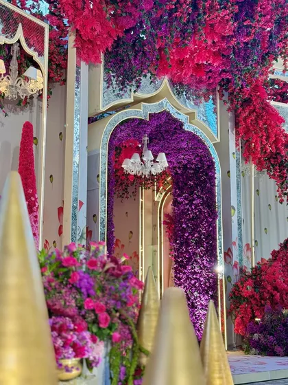 A dramatic floral archway, with purple flowers creating a tunnel of color, leading guests into the main celebration area.