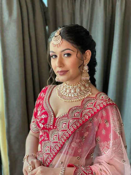 A beautiful portrait of this bride in her red wedding lehenga. Her makeup is soft and pretty, and her hair is styled in an intricate, textured braid.