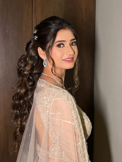 A side profile of the Sangeet ponytail, showing the soft curls and delicate accessories.