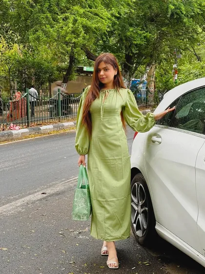 A beautiful green long-sleeved midi dress, perfect for a rainy day in Delhi. The color and style are both elegant and comfortable.