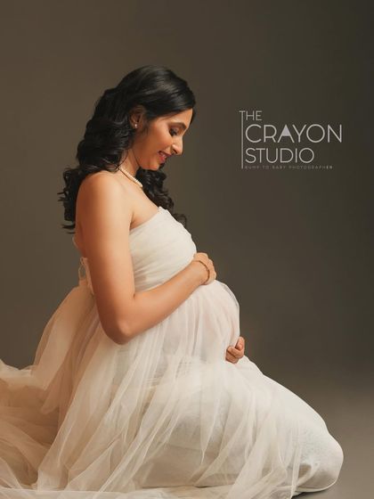 A seated profile portrait that feels incredibly gentle and intimate. The way she looks down at her bump, wrapped in soft white tulle, is a timeless image of a mother's love.