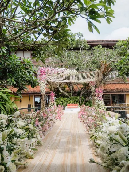 For a bride who wanted to be surrounded by nature, we designed this serene mandap set between trees and water in Sri Lanka. The aisle is lined with soft white and pink florals, leading to an open-air canopy for a pure and peaceful ceremony.