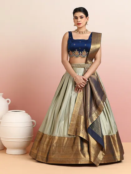 A sophisticated half-saree inspired lehenga in sage green and royal blue. The rich gold Banarasi border and draped dupatta create a look of modern royalty.