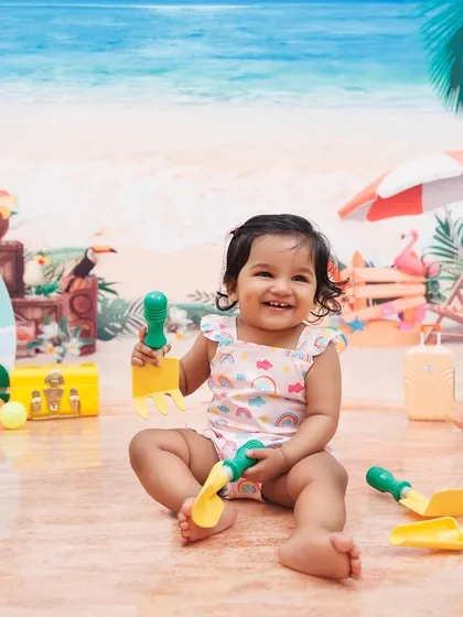 A happy smile from a little girl during her fun and sunny beach-themed first birthday photoshoot.