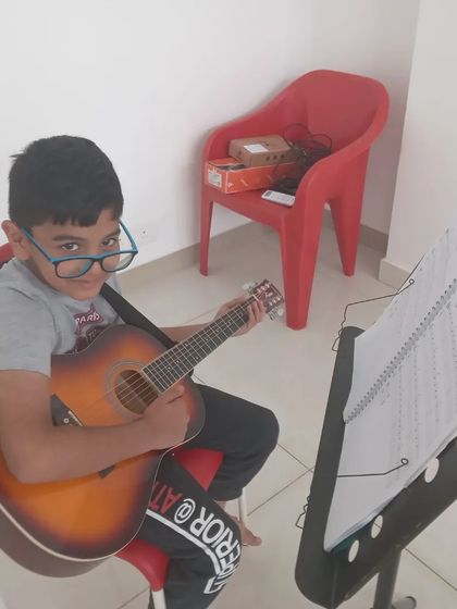 A young guitarist posing with his instrument, ready for his lesson.
