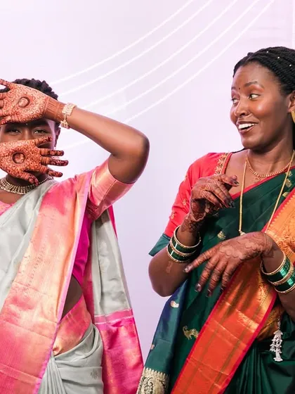 Fun and playful moments at a cross-cultural wedding. These two women in beautiful sarees share a laugh, showcasing the joy of blended celebrations.