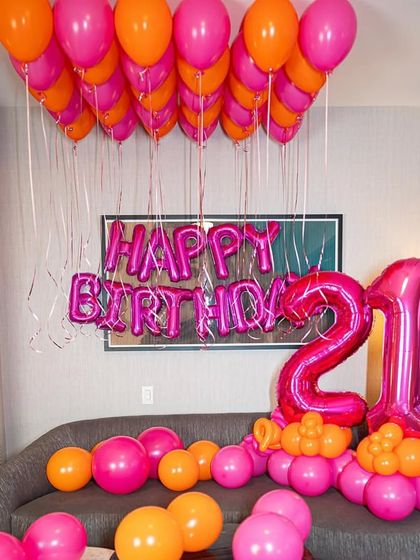 A close-up of the "Happy Birthday" and "21" foil balloons in a striking magenta color.