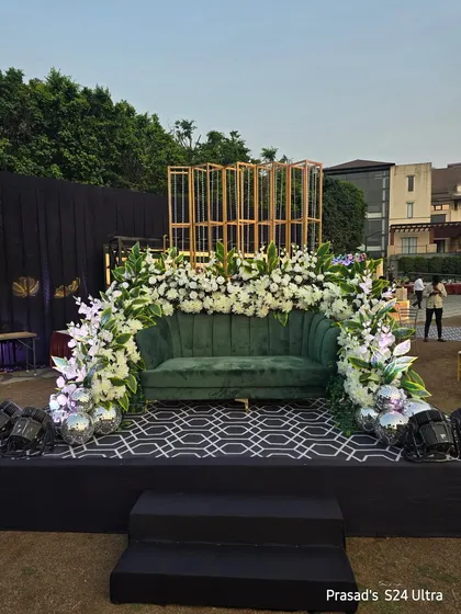 The full view of the green sofa photo area, set up on a low stage with a modern patterned floor.