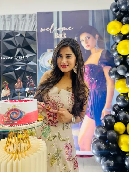 A welcome back party for BBK star Anusha Rai, featuring a custom banner, a 3D geometric wall, and a black and yellow color scheme.