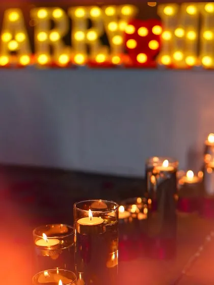I use lighting to create a warm, intimate glow. Here, floating candles in glass vases line the walkway, leading up to the softly blurred 'MARRY ME' letters in the background for a dreamy effect.