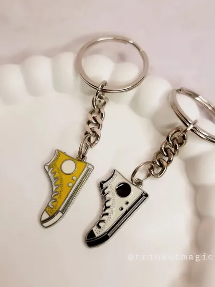 A pair of yellow and black sneaker charm keychains. The classic colors make them a stylish accessory for anyone.