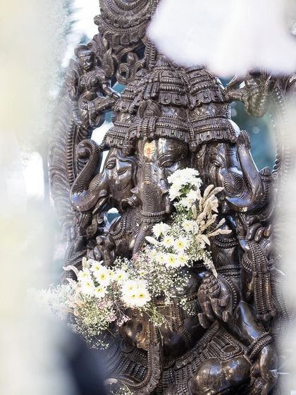 A close-up of the intricately carved Ganesha statue that served as the divine focal point for a wedding. Adorned with simple white flowers, it represents the blend of artistry and spirituality that I bring to my designs.