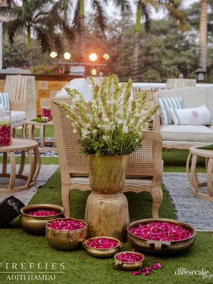 A beautiful arrangement of white tuberoses in a brass vase, surrounded by bowls of pink petals, creating a fragrant and visually stunning decor detail.