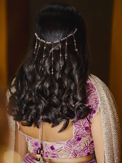 A detailed shot of this beautiful sangeeth hairstyle, featuring soft waves and a delicate, dangling hair accessory.