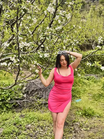 A confident pose among the apple trees, combining fashion with a stunning natural backdrop.