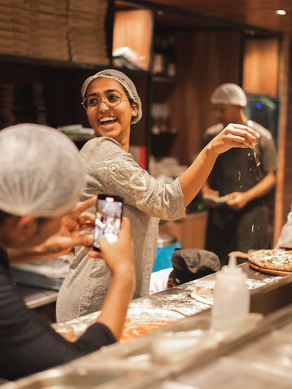 Our "Parm Queen" having fun while making pizzas, with a friend capturing the moment. It's all about enjoying the process.