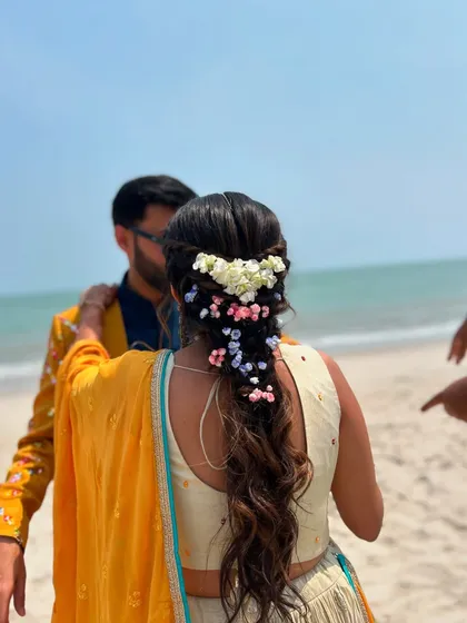 A candid moment from the beach Mehendi, with the bride's beautiful floral braid on full display.