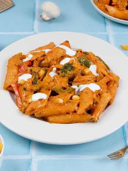 A plate of creamy mixed sauce pasta. We use styling to suggest freshness, with ingredients like corn and broccoli visible in the dish.