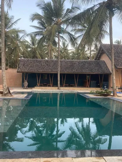 The recently completed farmhouse in Hassan, Karnataka, set within a coconut grove. The design features a large swimming pool as its centerpiece, with living spaces that open directly onto the deck.
