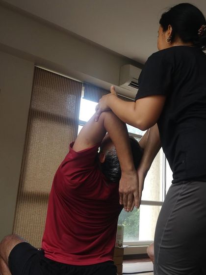 A student receives a gentle adjustment to open the shoulders and chest in a seated pose. This kind of hands on work helps release tension and improve posture.