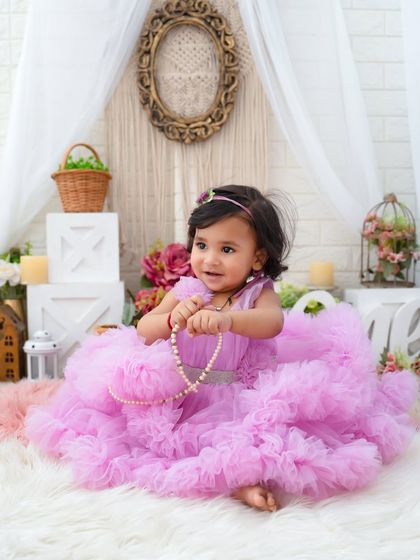 Playing with pearls in her purple princess dress. This candid moment captures the playful and curious nature of a toddler.