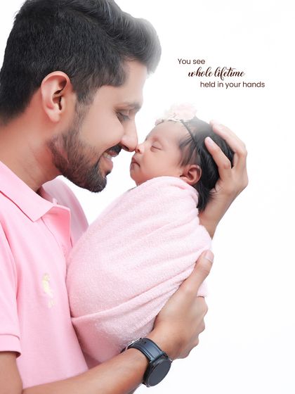 A whole lifetime held in your hands. A father holds his swaddled baby close, their noses touching, in a portrait that radiates warmth and paternal love.