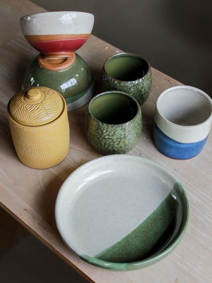 A lovely grouping of bowls and a lidded jar, featuring a harmonious palette of yellow, green, and blue glazes.
