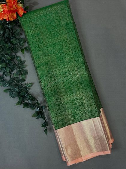 A rich green brocade saree with a contrasting pink and gold border.