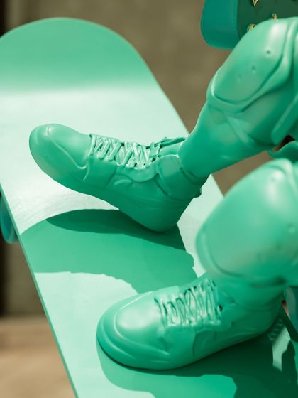 A detail of the sneakers and skateboard on the "Liberty in Motion" sculpture, grounding the iconic figure in contemporary street style.