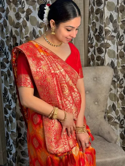 An elegant and classic look in a beautiful red and orange saree. The makeup is subtle yet defined, with a traditional bun hairstyle adorned with flowers.