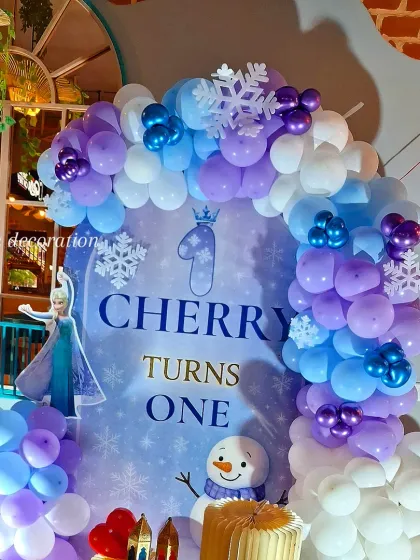 A closer look at the "Frozen" balloon arch and backdrop, showing the details of the character cutouts and snowflake decorations.