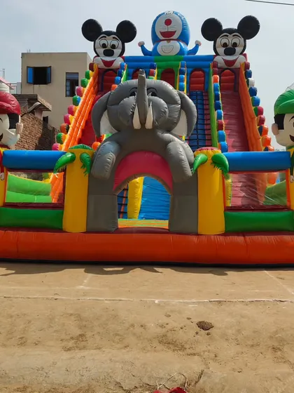 A big and colorful bounce house that combines multiple character themes like Mickey, Doraemon, and Mario. It features two large slides and a central tunnel entrance.