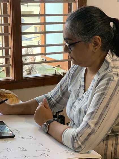 Practicing basic strokes and forms is a crucial part of the learning process. Here, a student follows along with a reference on her phone, building muscle memory and control.