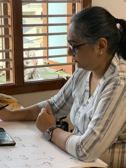 Practicing basic strokes and forms is a crucial part of the learning process. Here, a student follows along with a reference on her phone, building muscle memory and control.