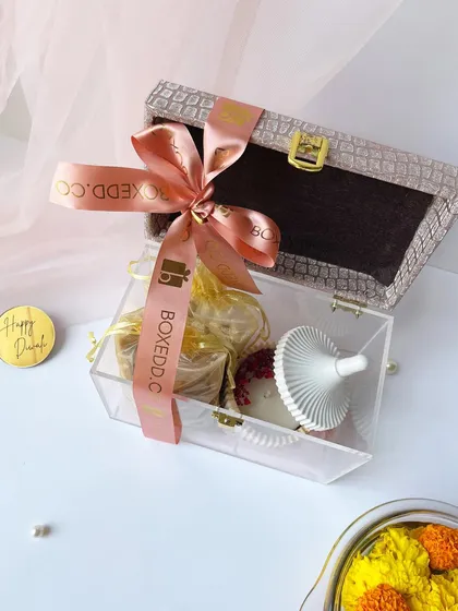 An exquisite acrylic box with a textured lid, filled with a scented candle and treats. This is a perfect example of how I create unique and modern Diwali gifts.