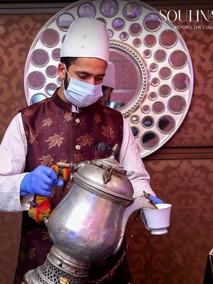 A server pouring traditional Kashmiri Kahwa from an ornate samovar, offering a warm and welcoming gesture to wedding guests. We incorporate unique cultural experiences into our service.