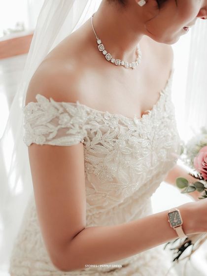 A close-up on the neckline of the bride's dress and her elegant diamond necklace, highlighting the beautiful details of her attire.