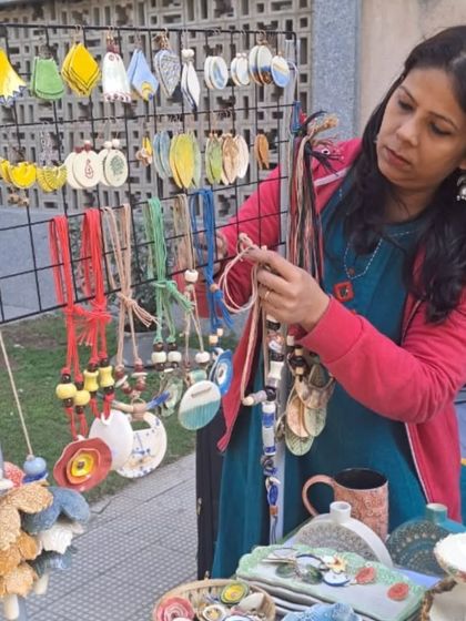 Here I am at the Delhi Potter's Market, arranging my display of handmade ceramic jewellery. The collection includes necklaces, chimes, and earrings in a variety of styles.