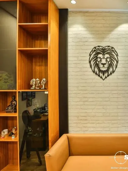 A cozy corner in an office space, featuring a comfortable leather sofa and a custom wooden bookshelf. The lion metal art on the brick-textured wall adds a touch of boldness and character.