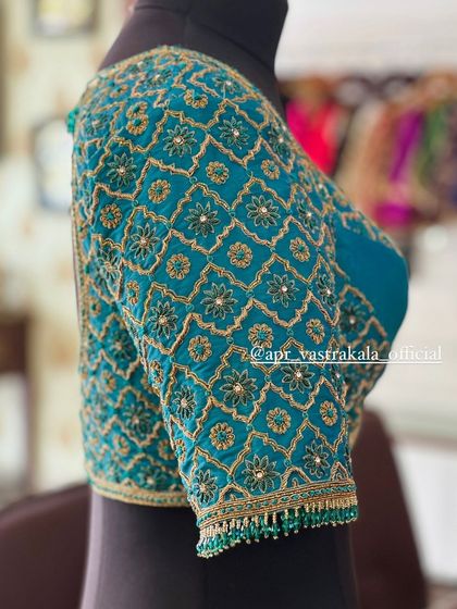 A side view of the teal blouse on a mannequin.