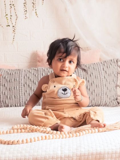 Like a fresh breeze. This little one is sitting on our cozy studio bed, looking so sweet and content. The lifestyle setup is perfect for capturing these simple, beautiful moments.