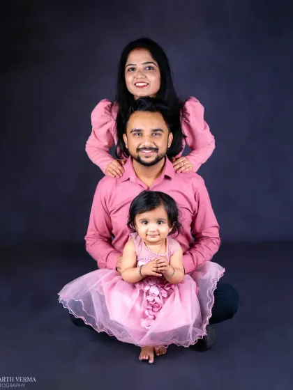 A classic family portrait with a fine-art touch. The coordinated outfits and creative pose against a dark backdrop create a stunning, artistic image that feels both timeless and modern.
