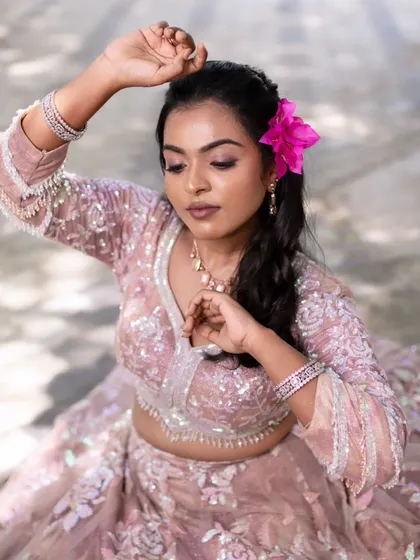 A model posing with a pink flower in her hair, adding a touch of playfulness to her glamorous look.