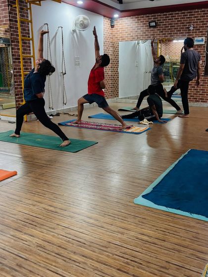 The energy of a group class, with students practicing variations of warrior poses and side angle poses, building heat and focus.